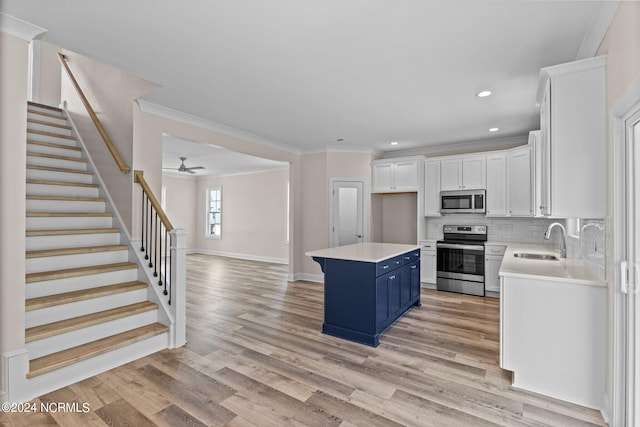 kitchen featuring a center island, sink, blue cabinetry, white cabinetry, and stainless steel appliances