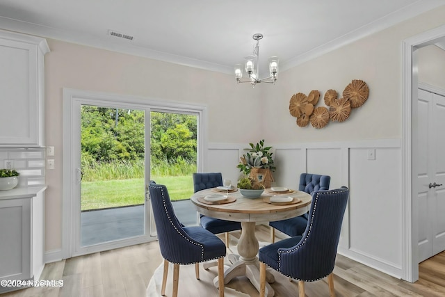 dining area featuring light wood-type flooring, crown molding, and an inviting chandelier