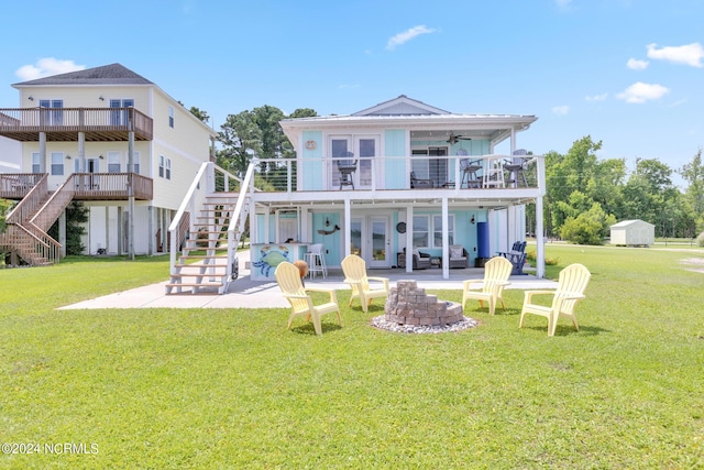 back of house featuring ceiling fan, a yard, an outdoor fire pit, a balcony, and a patio area