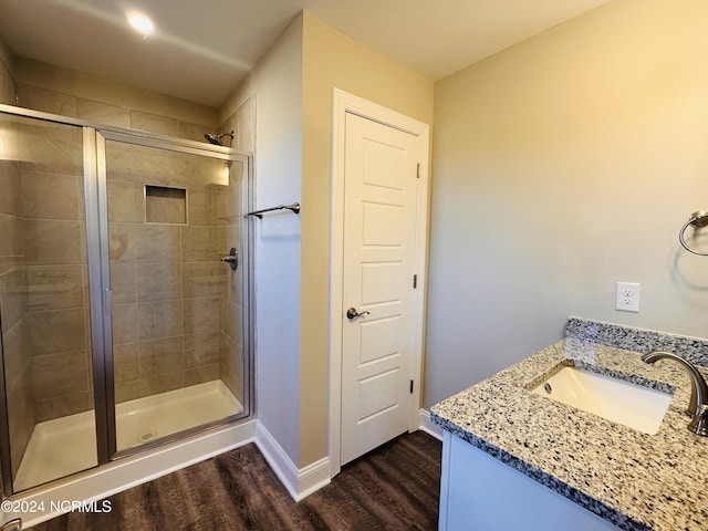 bathroom with walk in shower, vanity, and hardwood / wood-style flooring