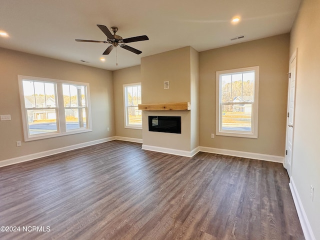 unfurnished living room featuring a healthy amount of sunlight, dark hardwood / wood-style floors, and ceiling fan