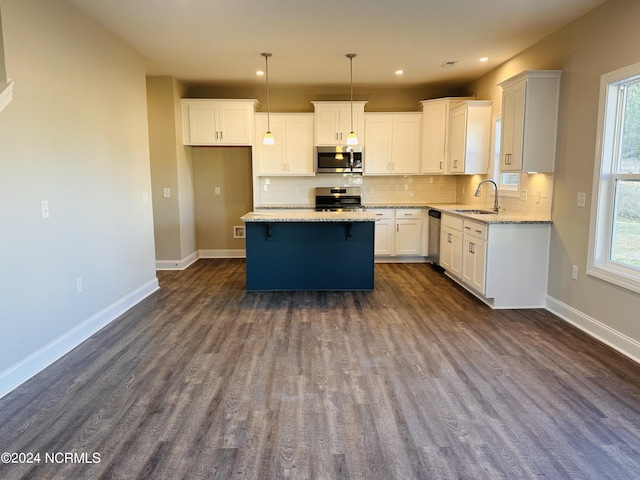 kitchen featuring dark hardwood / wood-style flooring, white cabinetry, stainless steel appliances, sink, and a kitchen island