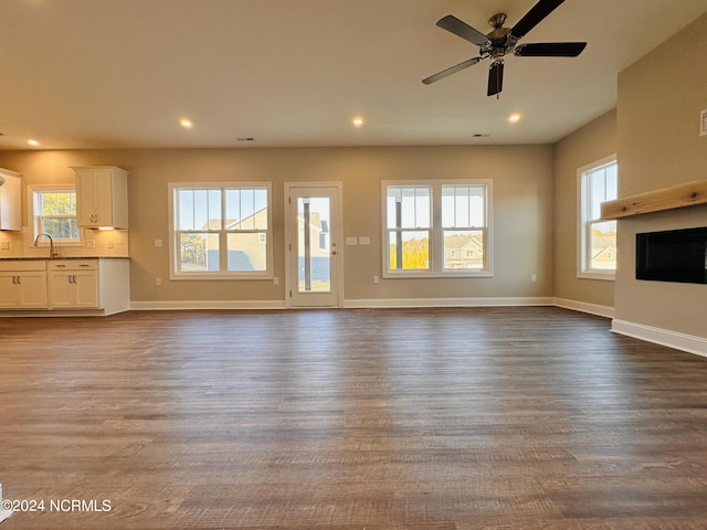 unfurnished living room featuring hardwood / wood-style floors, ceiling fan, and sink