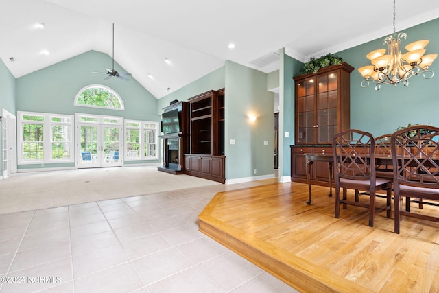 dining space with a towering ceiling, ceiling fan with notable chandelier, crown molding, and light colored carpet