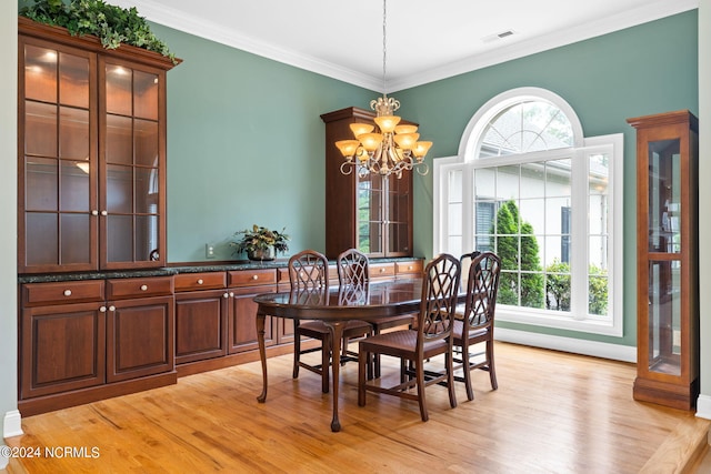 dining room with a wealth of natural light, an inviting chandelier, ornamental molding, and light hardwood / wood-style floors