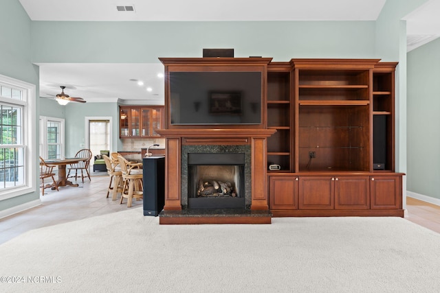 unfurnished living room with a premium fireplace, light colored carpet, and ceiling fan