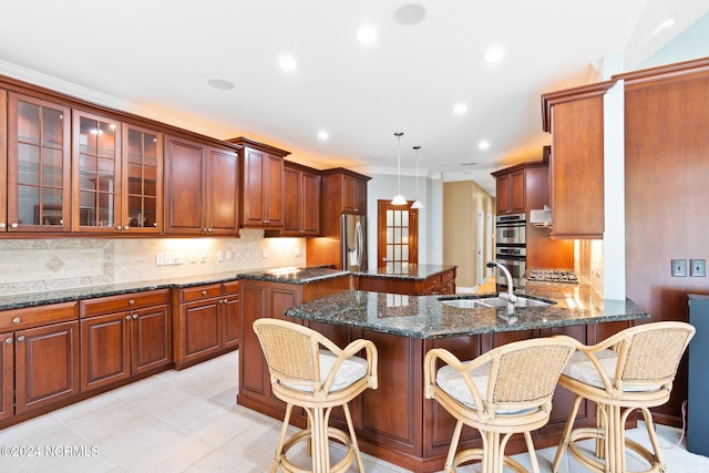 kitchen with decorative light fixtures, dark stone counters, light tile flooring, tasteful backsplash, and sink