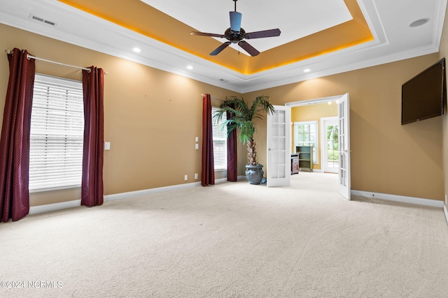 unfurnished room with ornamental molding, carpet floors, ceiling fan, and a raised ceiling