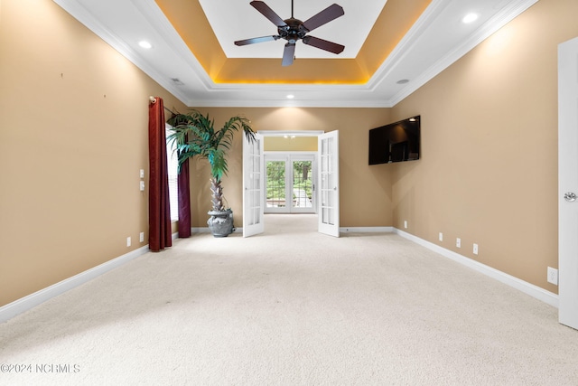 unfurnished room featuring ceiling fan, a raised ceiling, crown molding, carpet floors, and french doors