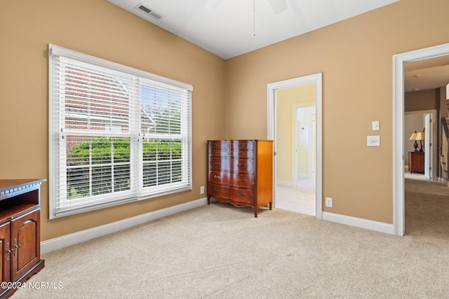 living area featuring a wealth of natural light, light carpet, and ceiling fan