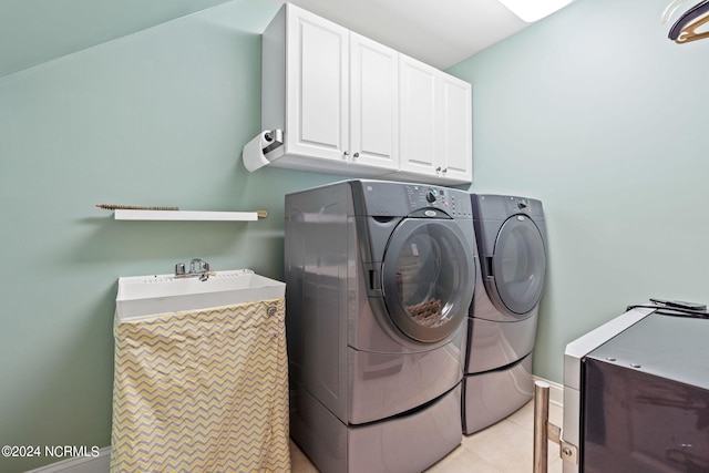 clothes washing area with cabinets, sink, light tile floors, and separate washer and dryer