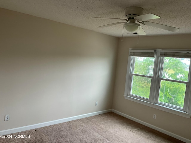 carpeted spare room featuring ceiling fan and a textured ceiling