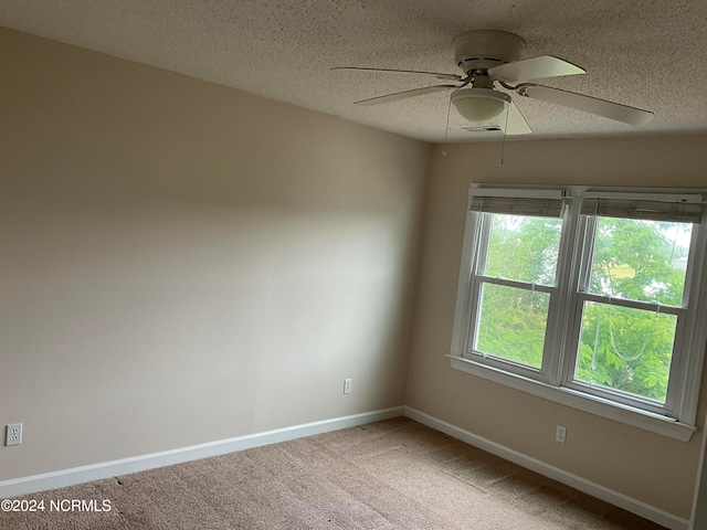 carpeted empty room with ceiling fan and a textured ceiling