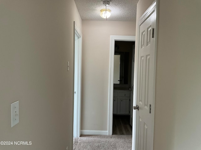 hallway featuring a textured ceiling and carpet