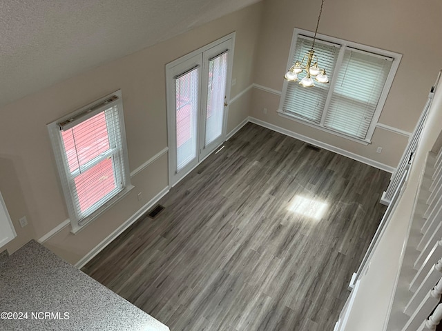 unfurnished living room featuring dark hardwood / wood-style flooring, a textured ceiling, and an inviting chandelier