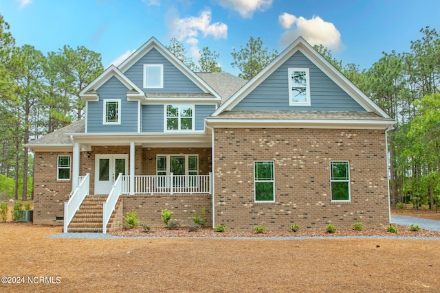 craftsman house with brick siding, covered porch, and french doors