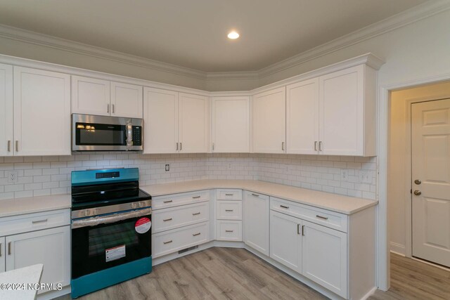 kitchen with white cabinets, backsplash, light wood-type flooring, and stainless steel appliances