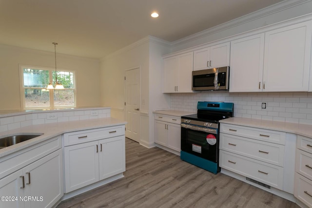 kitchen featuring appliances with stainless steel finishes, white cabinetry, visible vents, and crown molding