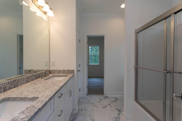 full bath with marble finish floor, double vanity, ornamental molding, a sink, and baseboards