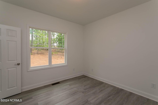 spare room with baseboards, visible vents, and dark wood finished floors