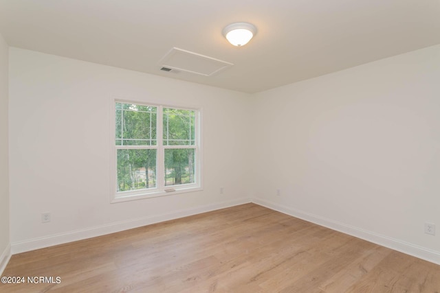 spare room with light wood-style floors, attic access, visible vents, and baseboards