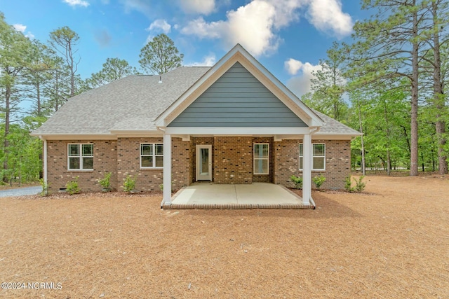 rear view of house featuring crawl space, a patio area, a shingled roof, and brick siding