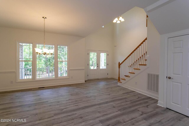 unfurnished living room with dark hardwood / wood-style floors, high vaulted ceiling, and an inviting chandelier