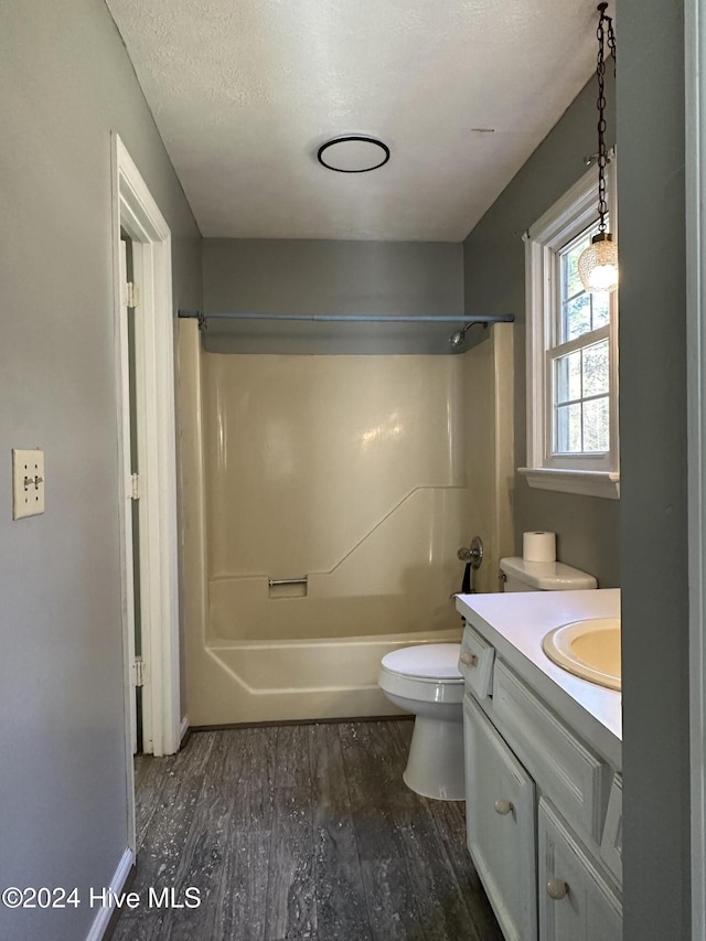 full bathroom with hardwood / wood-style floors, vanity, shower / washtub combination, toilet, and a textured ceiling