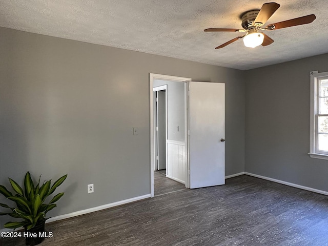 empty room with ceiling fan, dark wood-type flooring, and a textured ceiling