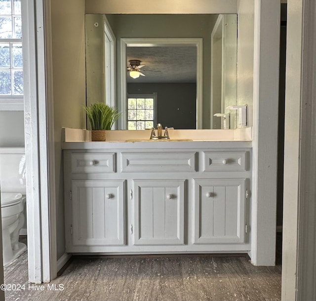 bathroom with wood-type flooring, vanity, toilet, and ceiling fan