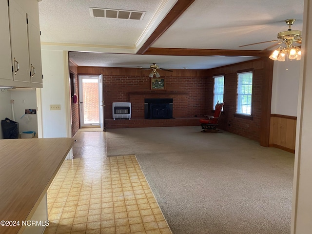 unfurnished living room with beamed ceiling, ceiling fan, and a healthy amount of sunlight