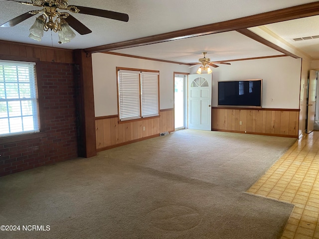 unfurnished living room featuring ceiling fan, carpet, and ornamental molding