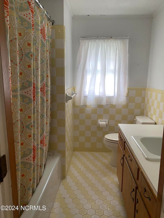 full bathroom with shower / bath combo with shower curtain, tile floors, tile walls, vanity, and toilet