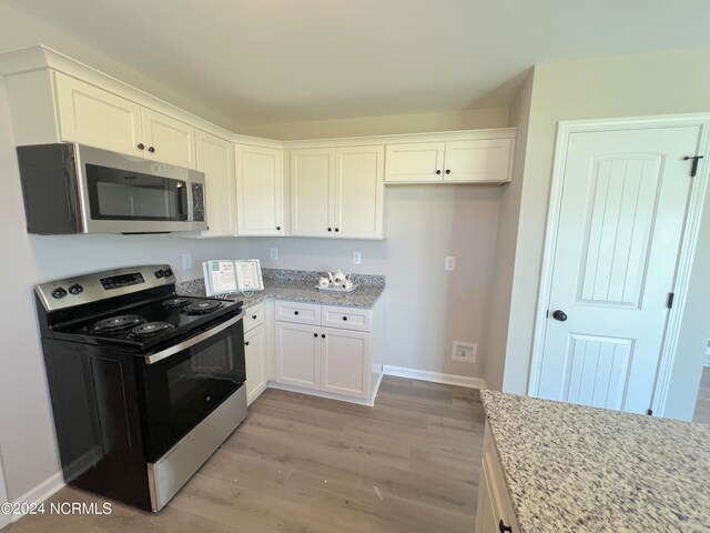 kitchen with electric range, stainless steel microwave, white cabinets, and light stone counters