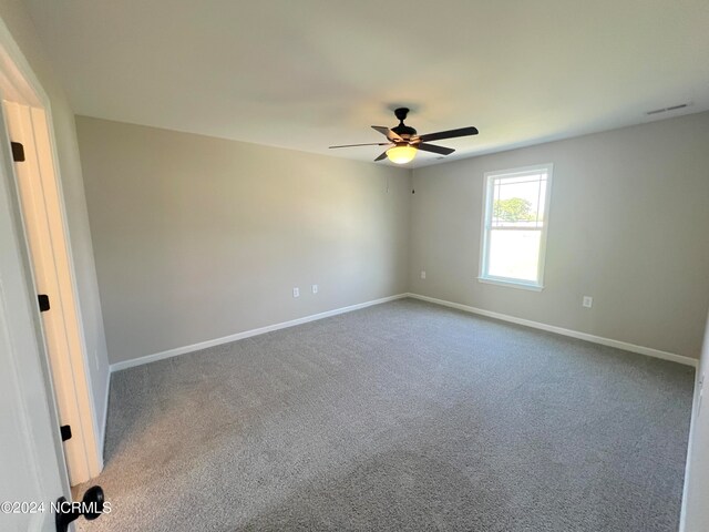 spare room featuring carpet, visible vents, ceiling fan, and baseboards