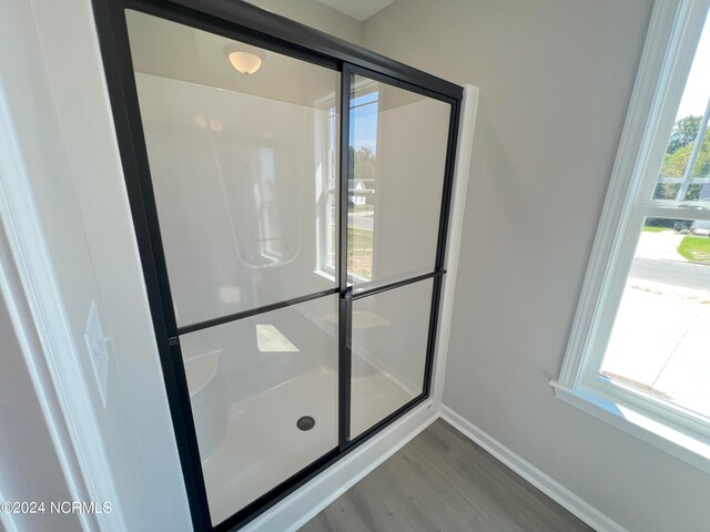 bathroom with a stall shower, baseboards, and wood finished floors