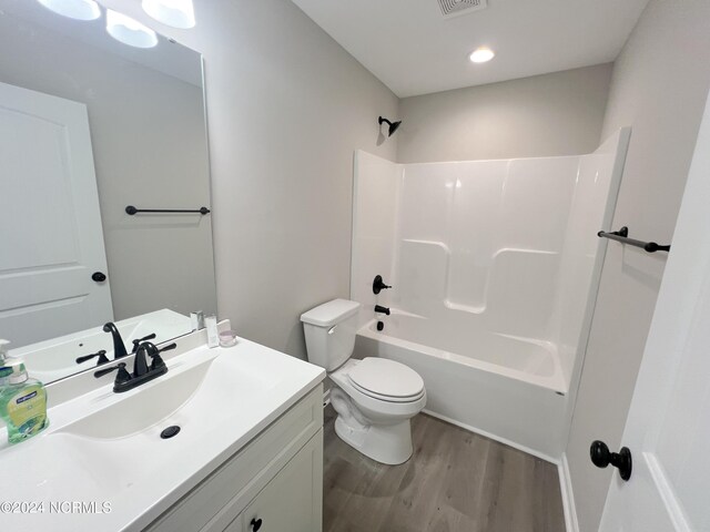 full bath with visible vents, toilet, wood finished floors, vanity, and shower / washtub combination