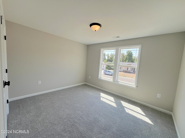 carpeted spare room featuring visible vents and baseboards