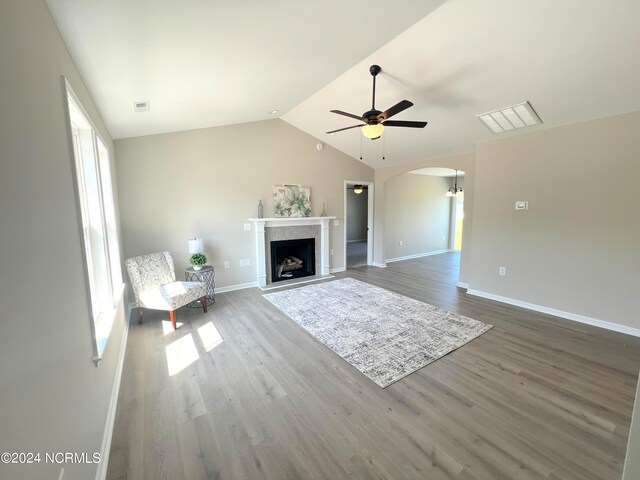 unfurnished living room with arched walkways, wood finished floors, visible vents, and a premium fireplace