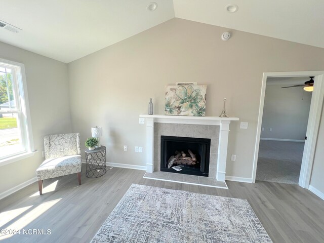 unfurnished room with lofted ceiling, a fireplace, visible vents, and wood finished floors