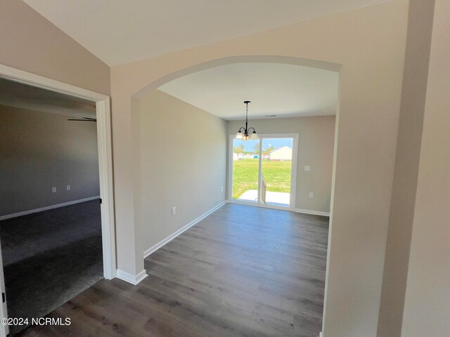 unfurnished dining area with arched walkways, dark wood-style flooring, and baseboards