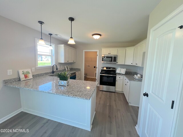 kitchen featuring stainless steel appliances, wood finished floors, a peninsula, and light stone countertops