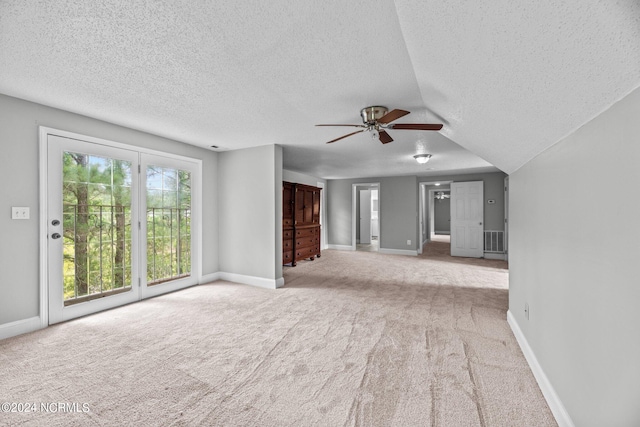 unfurnished living room featuring a textured ceiling, carpet flooring, ceiling fan, and vaulted ceiling