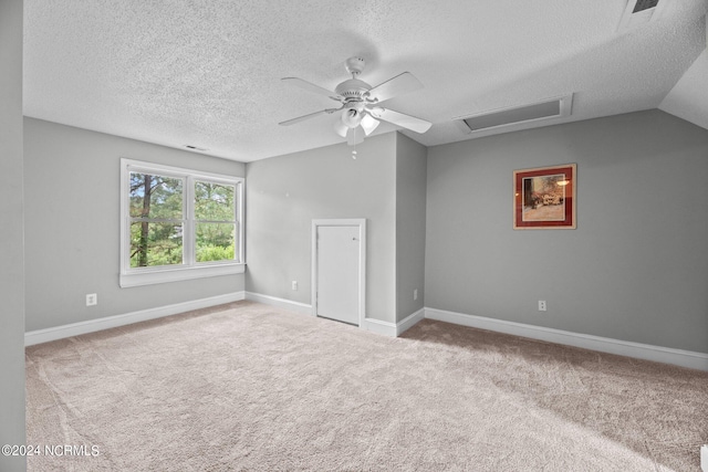 carpeted empty room with lofted ceiling, ceiling fan, and a textured ceiling