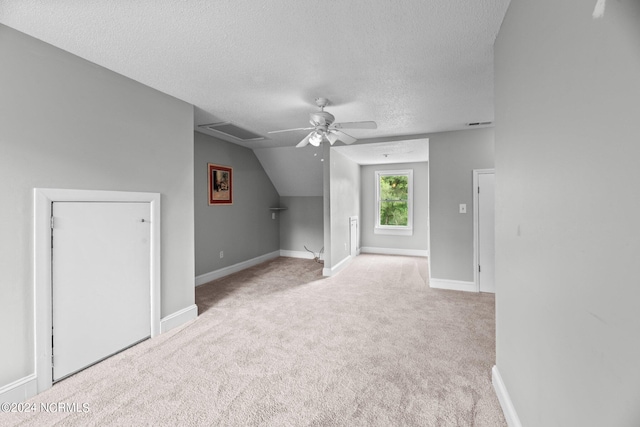 carpeted empty room featuring lofted ceiling, ceiling fan, and a textured ceiling