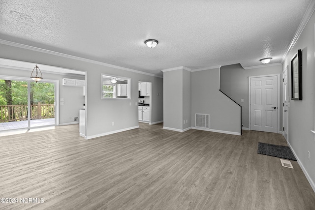 unfurnished living room featuring a textured ceiling, ornamental molding, and light wood-type flooring