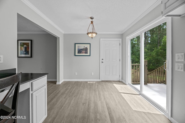 foyer entrance with crown molding, a textured ceiling, and light hardwood / wood-style flooring