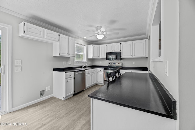 kitchen with light wood-type flooring, appliances with stainless steel finishes, white cabinetry, and ceiling fan