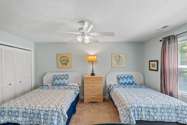 carpeted bedroom featuring a closet, ceiling fan, and a textured ceiling