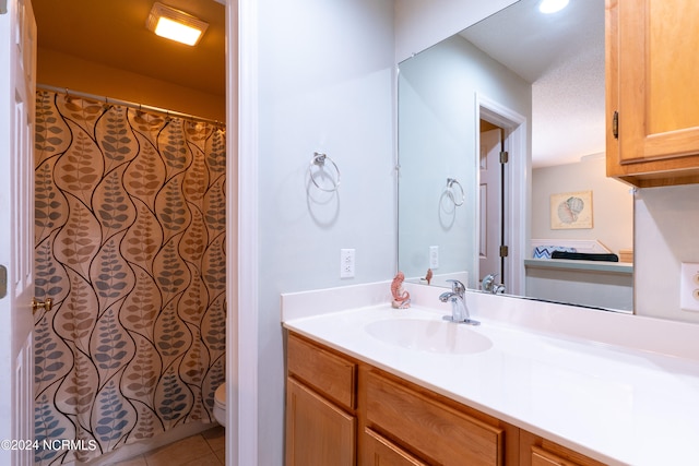 bathroom featuring tile flooring, toilet, and vanity